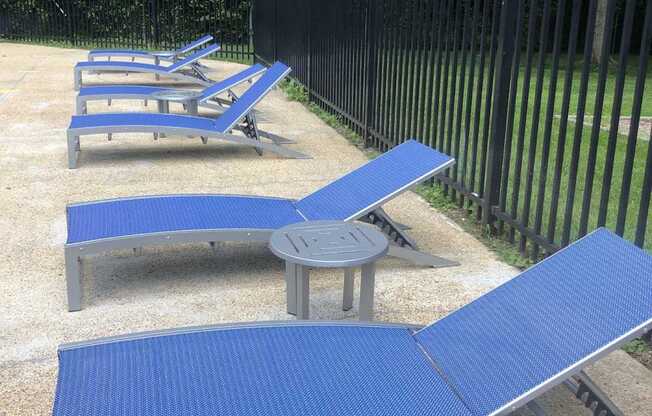 A set of blue sun loungers and tables are arranged in a row.