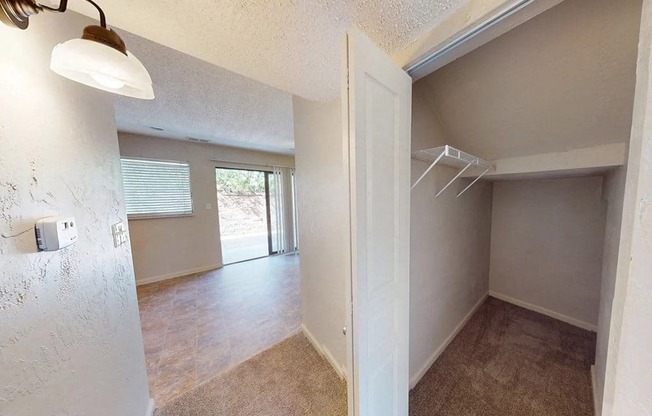 an empty living room with a closet and a door to a bedroom