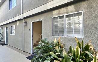 the front of a building with plants in front of it