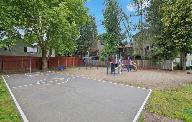 A basketball court is surrounded by a fence and trees.