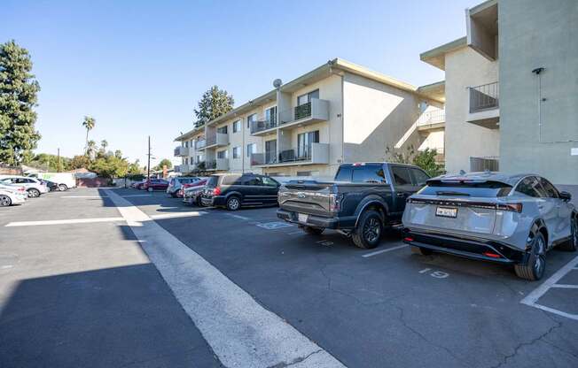 a parking lot with cars parked in front of an apartment building