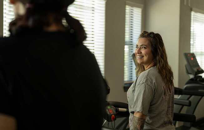 A woman with a tattoo on her arm is standing in a gym.