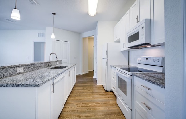 a kitchen with white cabinetry and granite countertops