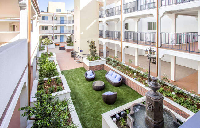 a courtyard with a fountain and green grass