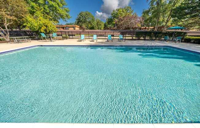 Heated pool equipped with comfy lounge chairs at Westwood Village Apartments in Westland, MI