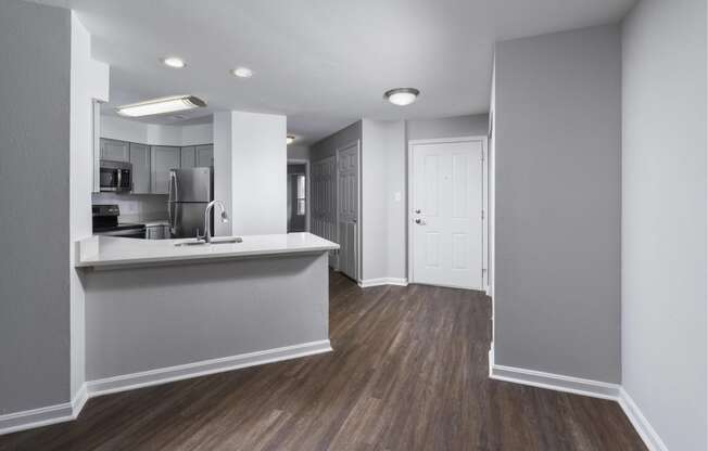 an empty apartment with a kitchen and a door to a hallway