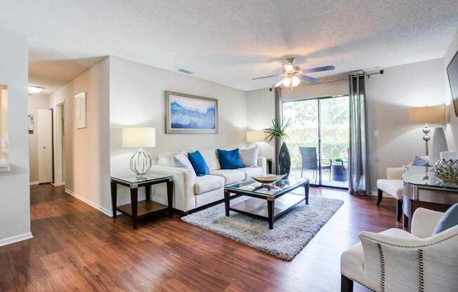A living room with a white couch and a painting on the wall.