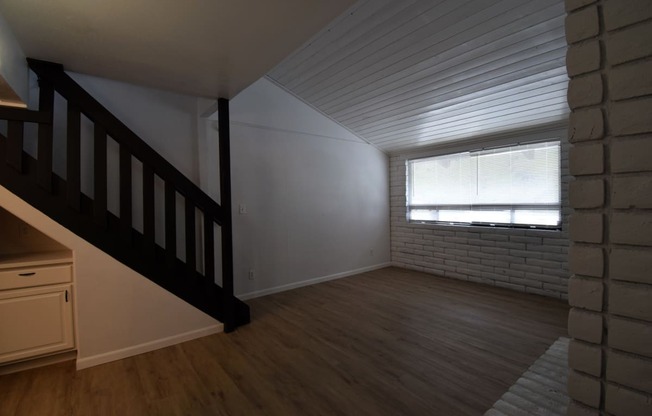 an empty living room with a staircase and a window
