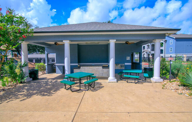 a covered patio with picnic tables in front of a building