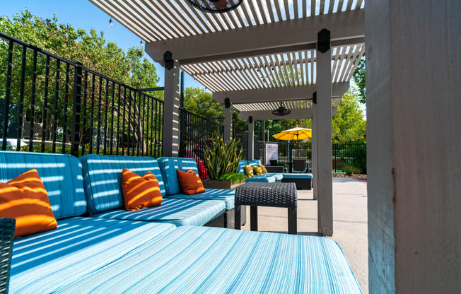a patio with blue couches and tables and a pergola