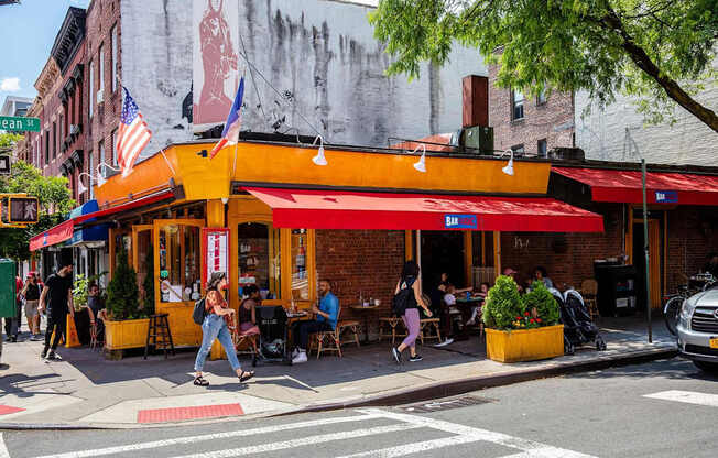 people walking down the street in front of a restaurant at The Paxton, Brooklyn, NY 11201