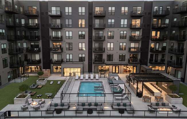 A modern apartment complex with a pool and outdoor seating area.