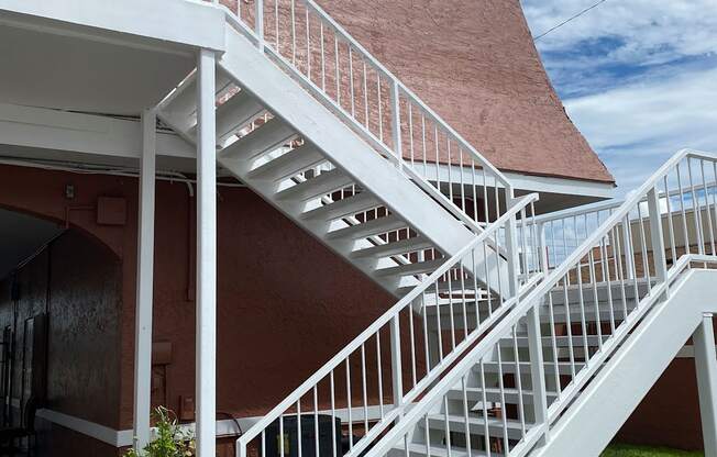 a white staircase on the side of a building with a cloudy sky in the background at Colonial Apartments, Orlando, FL