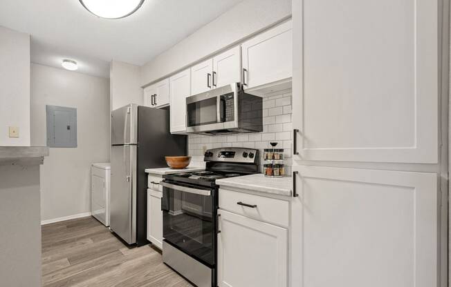 a renovated kitchen with white cabinets and stainless steel appliances