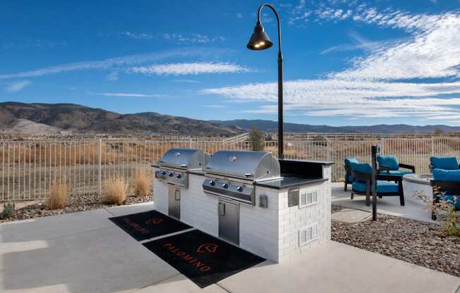 two stainless steel grills on a patio with mountains in the background