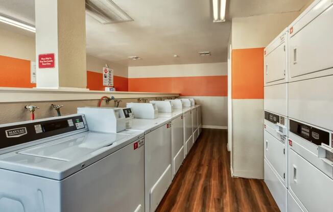 a laundry room with washers and dryers and a row of white appliances