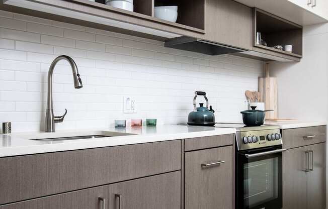 A modern kitchen with a stove, sink, and cabinets.