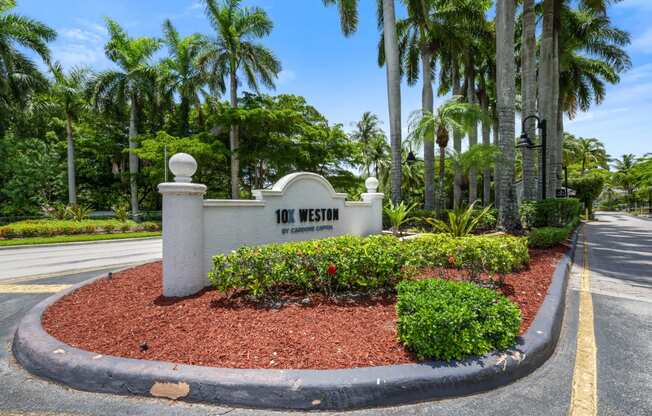 the sign at the front of the 100 west entrance to the community with palm trees