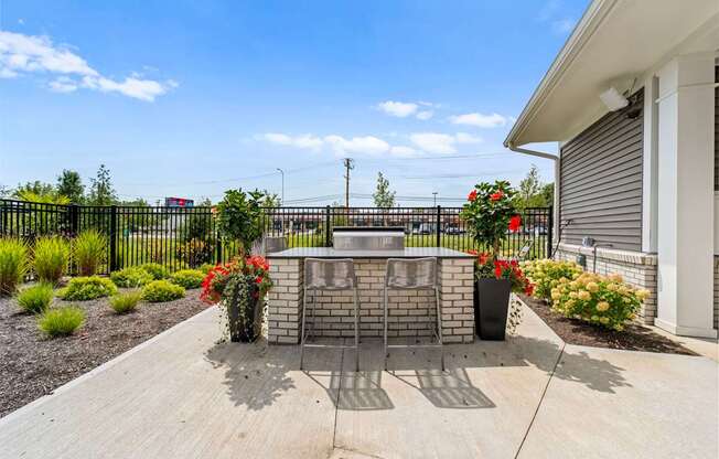 A black fence with a gate and a brick pillar with a planter on top.