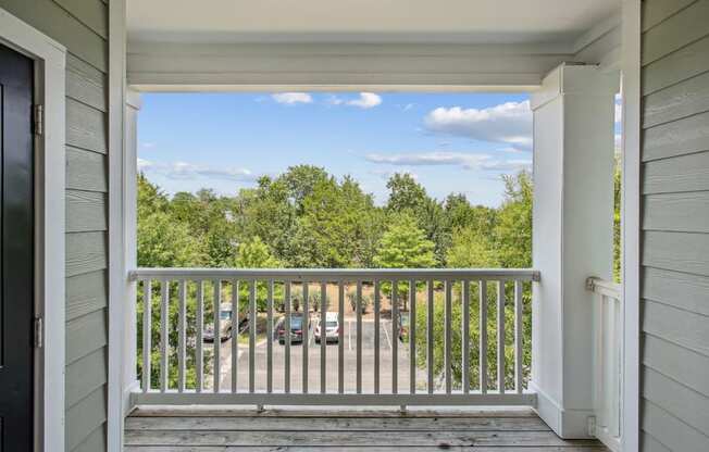 a balcony with a view of a parking lot and trees