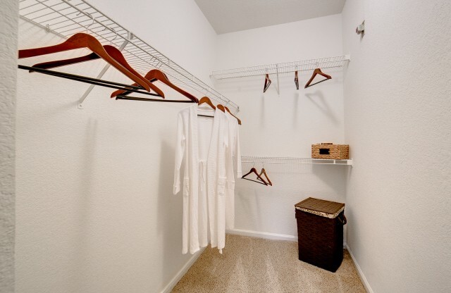 View of Classic Apartment Interior, Showing Closet with Hangers, Clothes Hanging, and Hamper at Stonebriar of Frisco Apartments