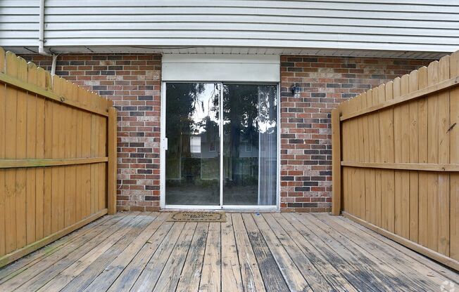 the deck of a brick house with a sliding glass door