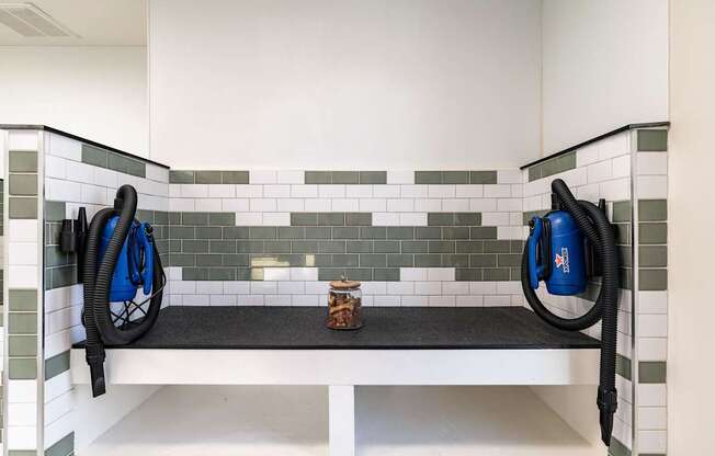 A black vacuum cleaner is on the left side of a white bench with a black vacuum cleaner on the right side.