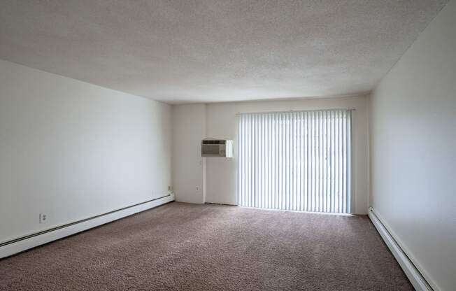 the living room of an apartment with a large window and white walls. Coon Rapids, MN Robinwood Apartments