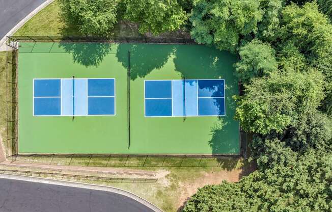 Two tennis courts surrounded by trees.