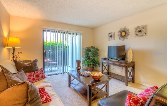 A living room with a couch, a coffee table, a television, and a window with blinds.