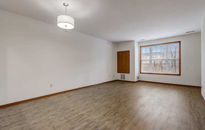 an empty living room with wood floors and a window