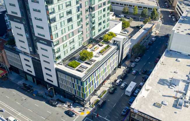A tall building with a green roof is surrounded by other buildings and busy streets.