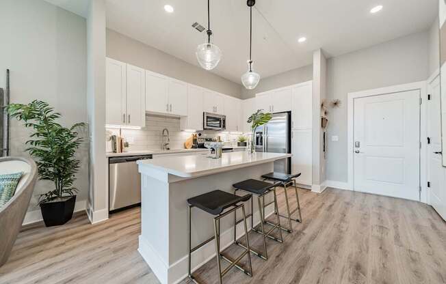 A modern kitchen with a white island and bar stools.