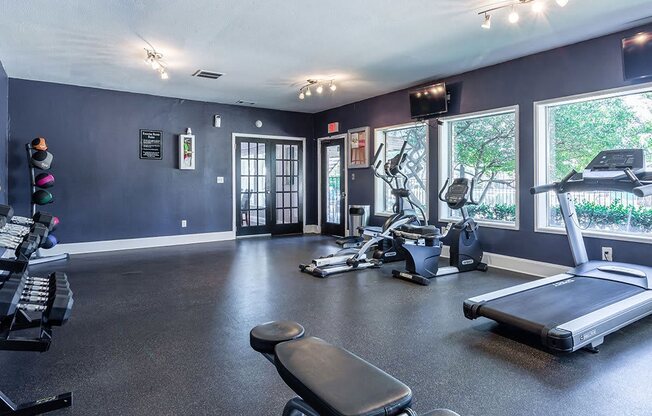 the gym has plenty of exercise equipment and windows