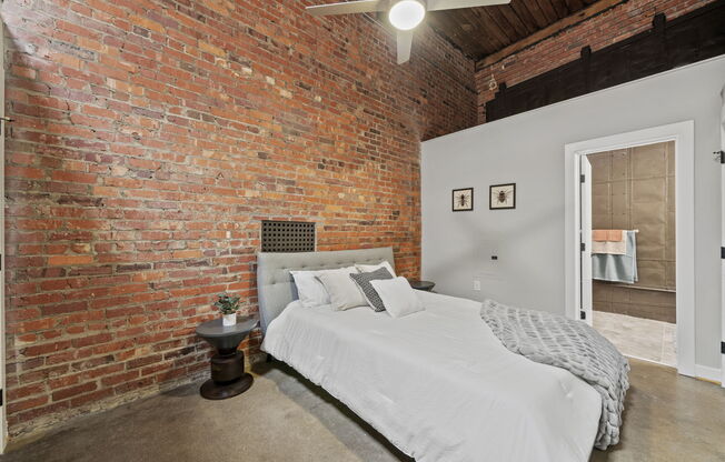 a bedroom with a bed and a exposed brick wall