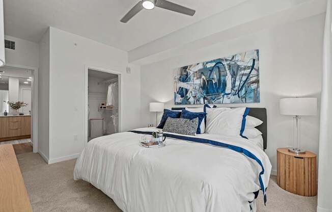 A bedroom with a large bed and a painting on the wall.