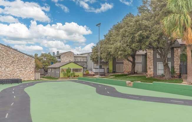 a green court in front of a building with apartments in the background