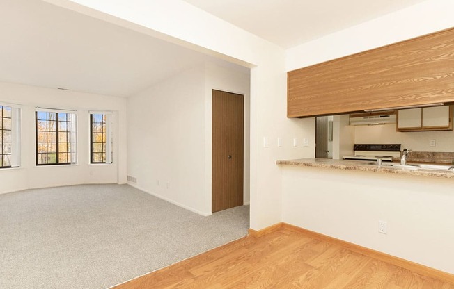 an empty living room and kitchen with a wood floor