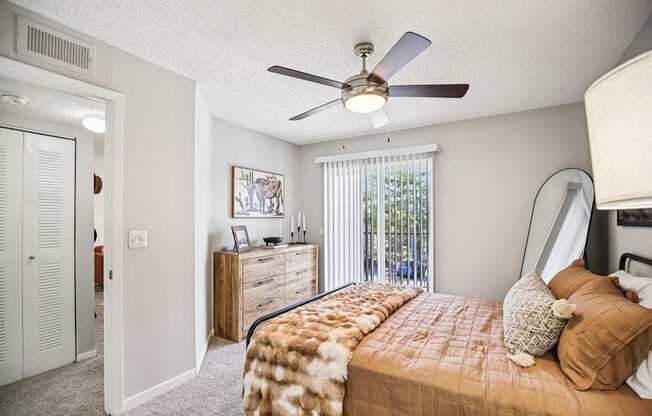 A bedroom with a bed, dresser, and a ceiling fan.