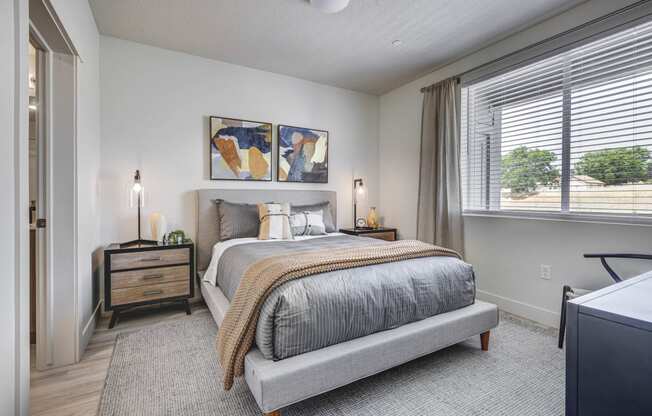 Angled shot of bedroom showing large window, and decorated bed