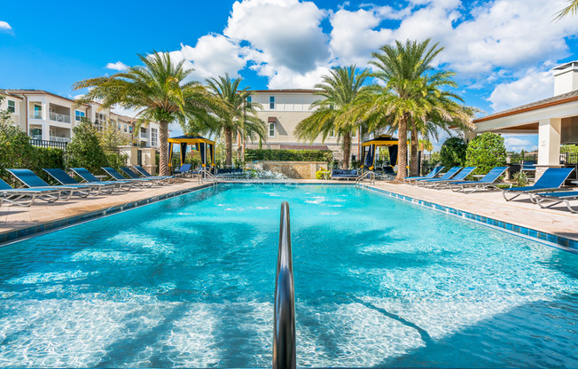 View of Pool Area, Showing Loungers, Cabanas, Palm Trees, and Outdoor Couches at The Marq Highland Park Apartments