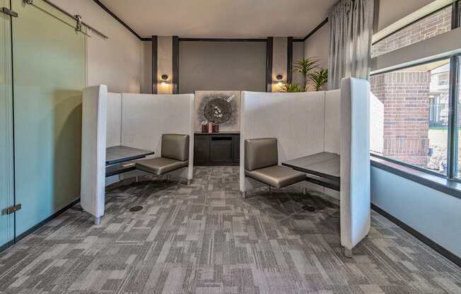 A room with grey carpet and two white booths with a fan in the middle.