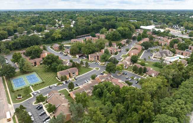 A bird's eye view of a residential area with a tennis court.
