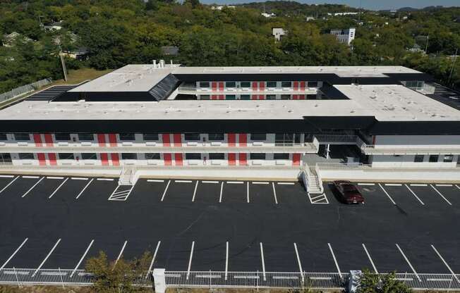 A parking lot in front of a building with a car parked in it.