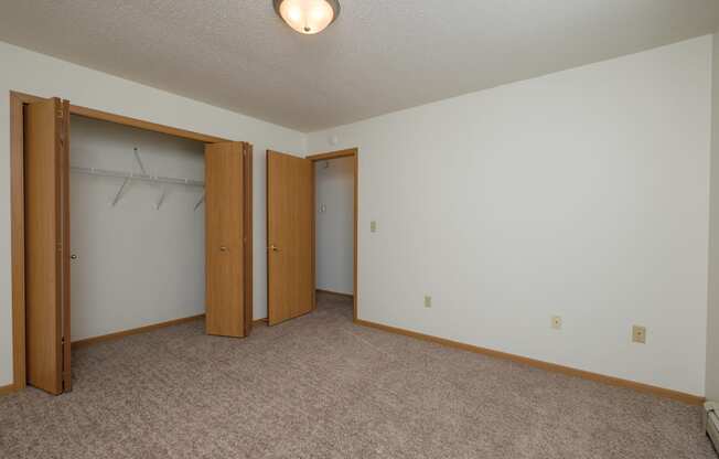 an empty room with two doors and a closet. Fargo, ND Twin Parks Apartments.