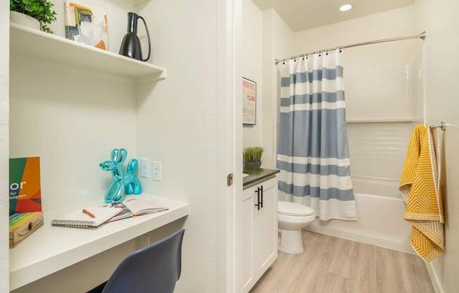 A small bathroom with a white desk and a blue chair.