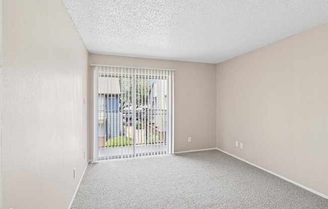 A5 bedroom with a carpeted floor and a sliding glass door leading to a balcony at Windridge on the Parkway in Dallas, TX
