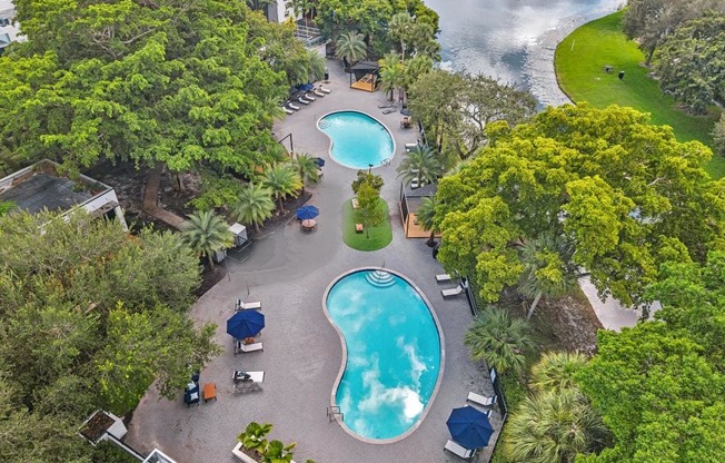 A large outdoor swimming pool surrounded by trees and lawn chairs.