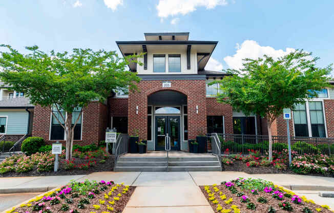 the front entrance of a brick building with trees and flowers