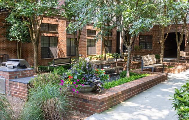 a courtyard with benches and trees in front of a brick building